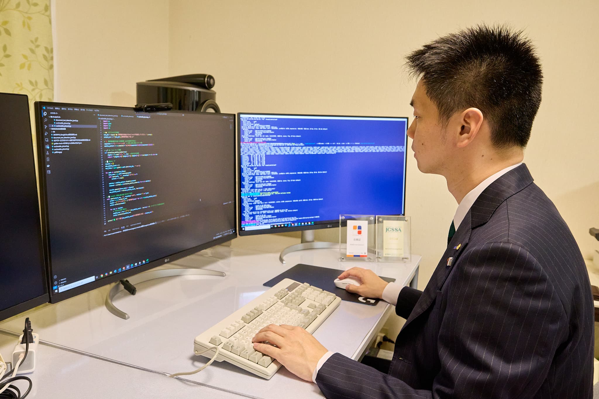 デュアルディスプレイでコーディング作業、スーツ姿