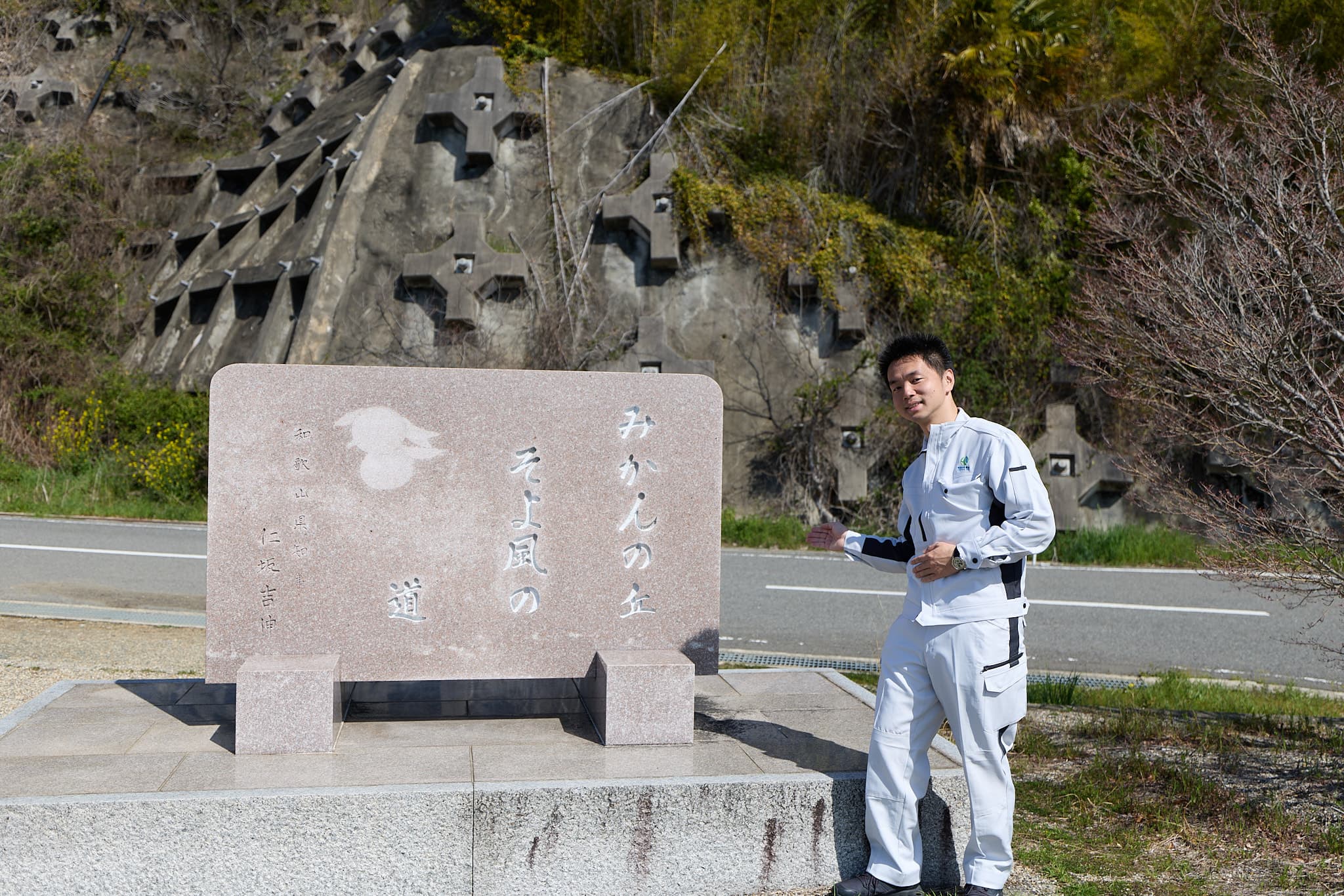 「みかんの花咲く丘」石碑前、作業着姿